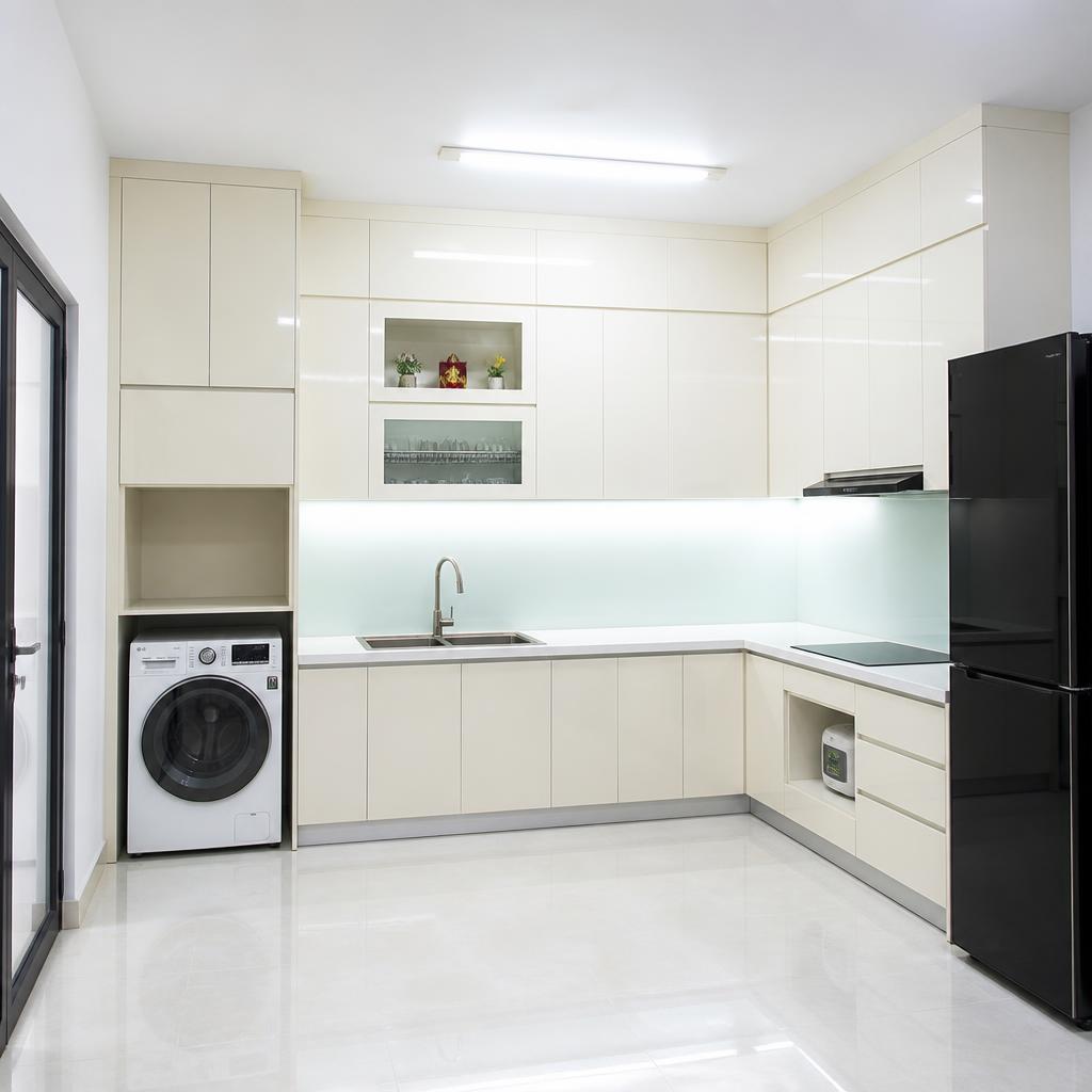 Tủ bếp nhựa PVC màu trắng sữa, bề mặt bóng gương, hốc máy giặt âm tủ dưới, khu vực bếp nhà phố nhỏ, ánh đèn huỳnh quang trắng, chụp góc rộng thấy toàn bộ hệ tủ