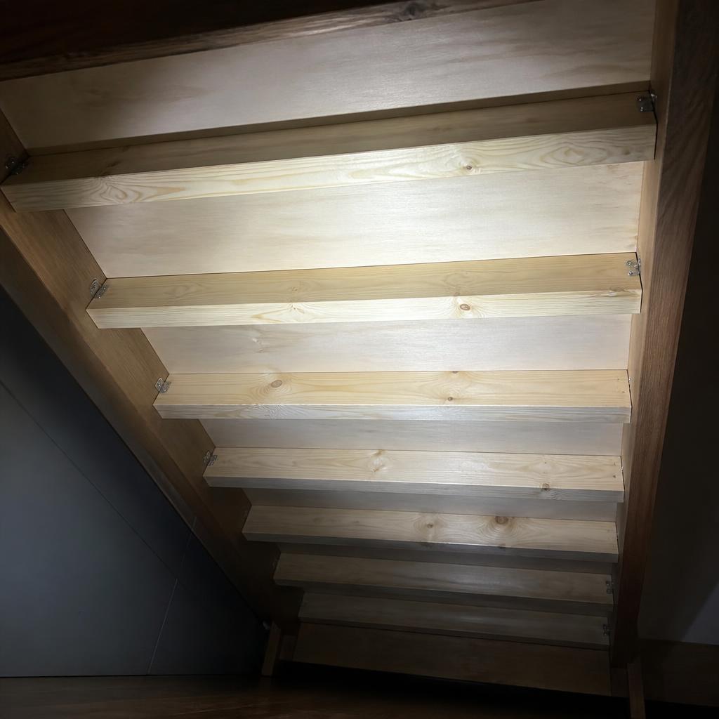 Mặt dưới tấm sàn giường plywood 18mm, thể hiện hệ 6 thanh đỡ ngang bằng gỗ thông 40×60mm khoảng cách 28cm, góc chụp từ dưới lên bằng đèn pin, ánh sáng tạo bóng đổ rõ cấu trúc gia cường, nệm foam đã được nhấc lên