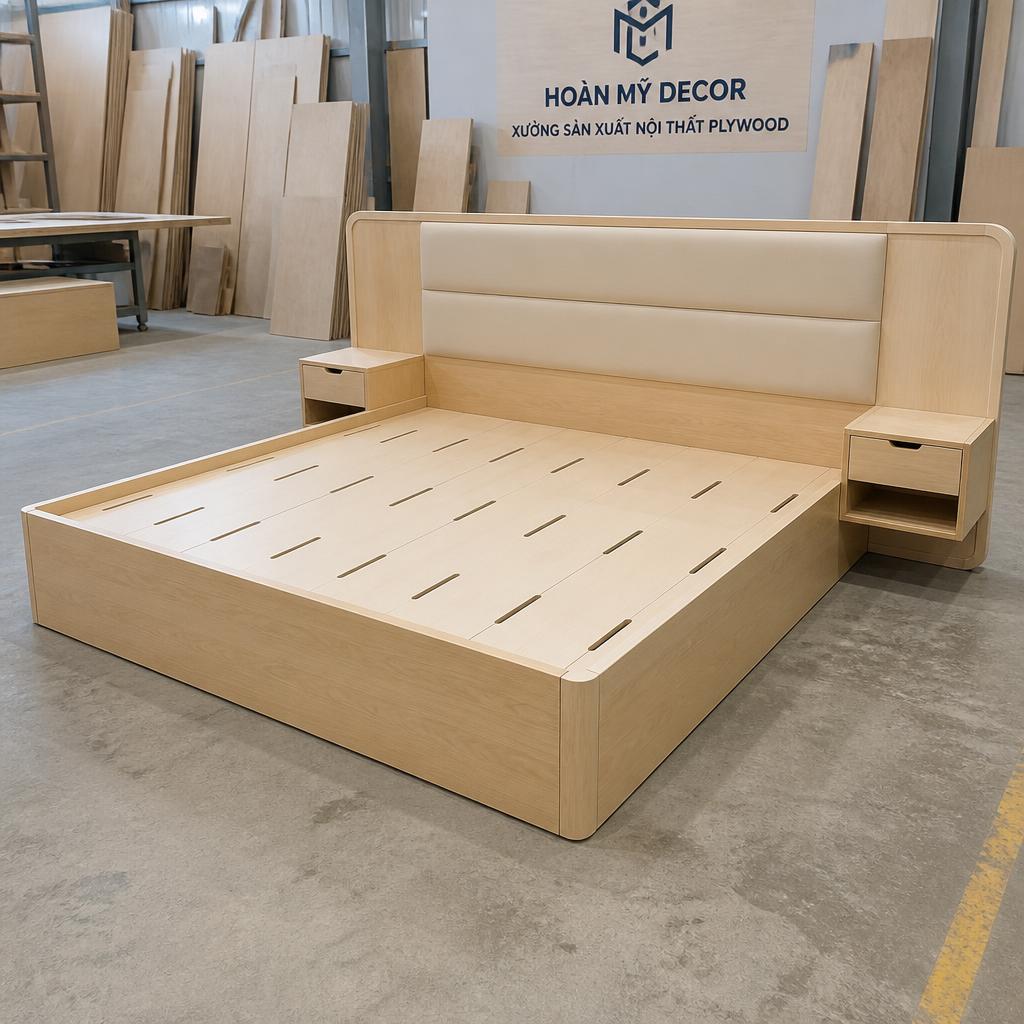 Sản phẩm giường plywood hoàn thiện tại xưởng Hoàn Mỹ Decor trước khi đóng gói vận chuyển, góc chụp 3/4 từ phía trước, ánh sáng xưởng đều, thể hiện chất lượng hoàn thiện bề mặt và độ kín khít các cạnh