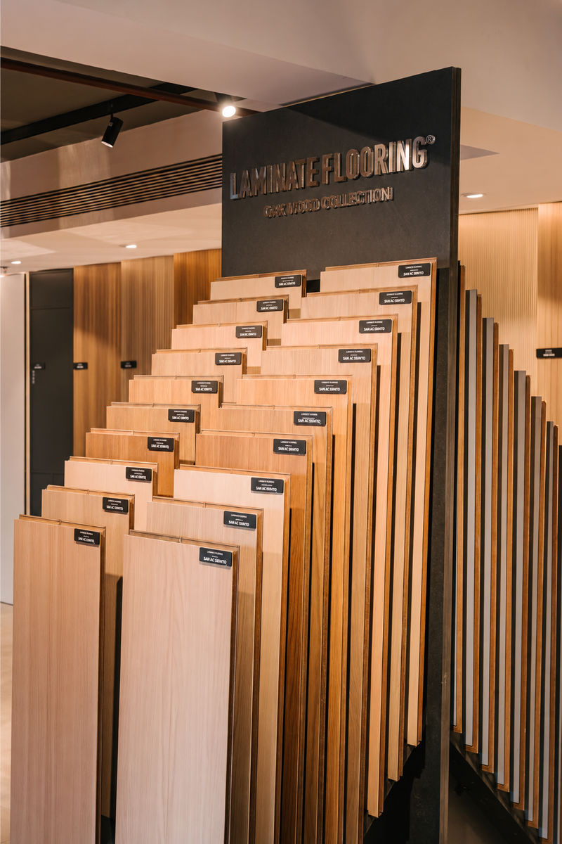 Giá trưng bày các mẫu sàn vân gỗ dưới bảng Laminate Flooring của An Cường.