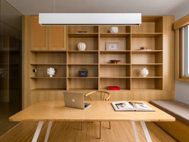 Phòng làm việc vân gỗ sáng với bàn rộng và giá sách lớn
