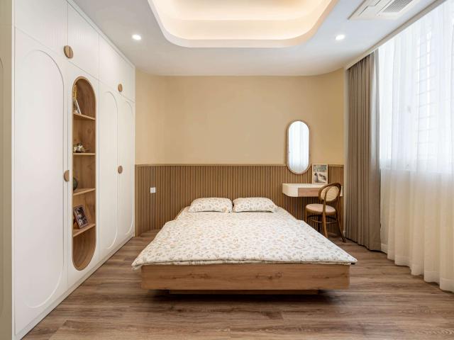 Phòng ngủ master sáng với giường vân gỗ và tủ hốc vòm