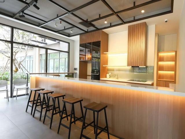 Bếp mở có đảo dài kiêm quầy bar và hệ tủ vân gỗ