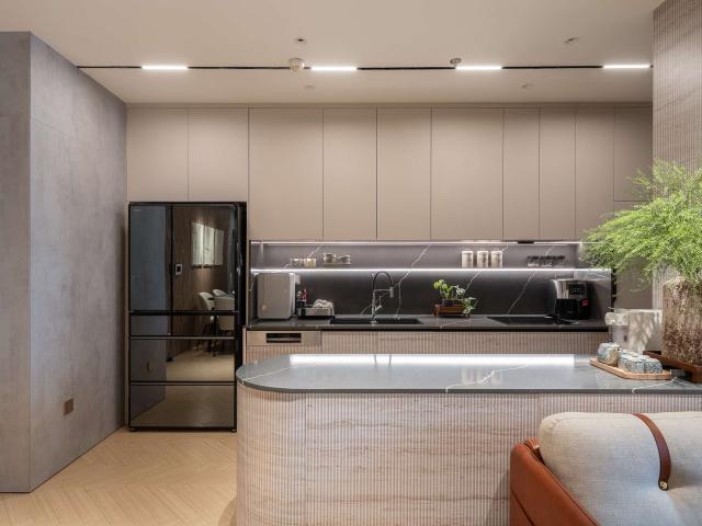 Tủ bếp tông xám be với đảo bo cong và đèn LED